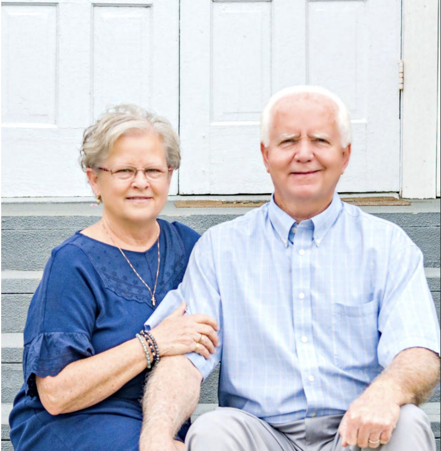 Pastor Wayne and Debbie Holcomb sitting together on the church steps